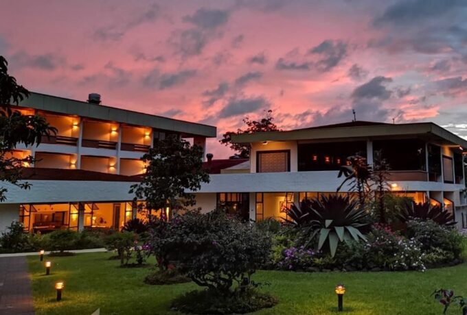 Illuminated facade of Hotel Bougainvillea in Costa Rica at sunset with tropical gardens