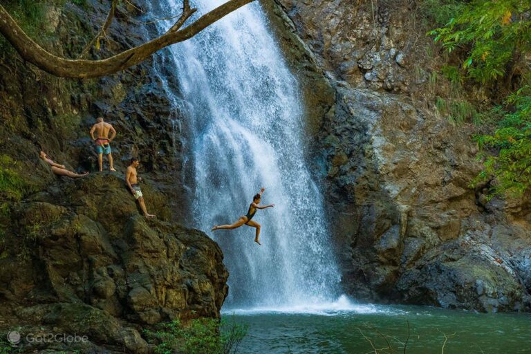 Woman junping in the Montezuma Waterfall - Costa Rica